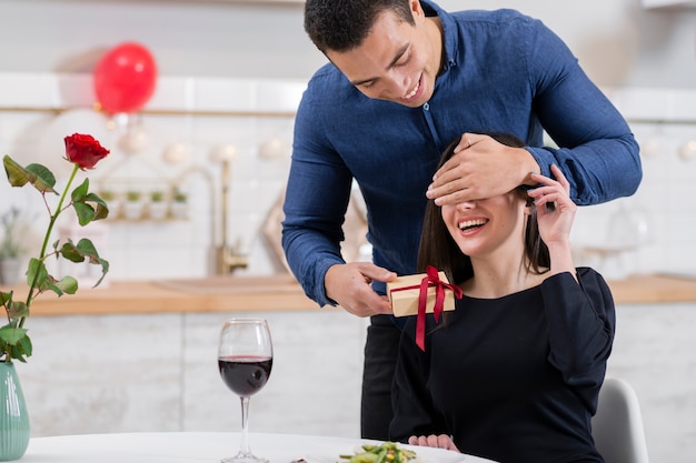 Man die de ogen van zijn vriendin bedekt voordat hij haar een geschenk geeft