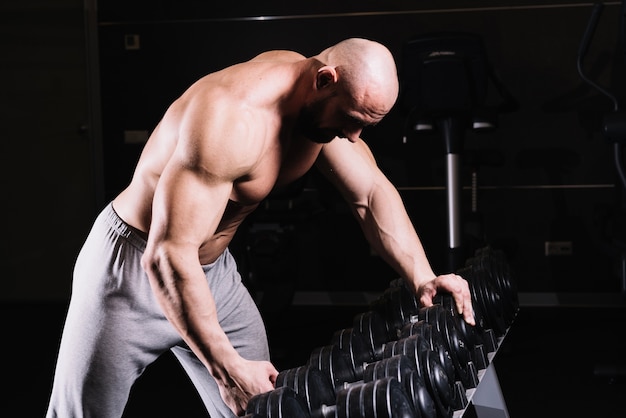 Gratis foto man die dumbbell uit rek neemt