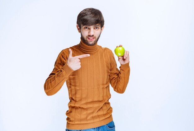 Man die een groene appel vasthoudt en deze promoot bij de klanten.