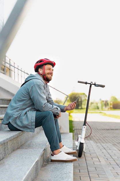 Man die een pauze neemt na het rijden op zijn scooter
