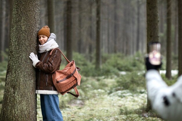 Gratis foto man die foto's maakt van een vrouw tijdens een winterse roadtrip in het bos