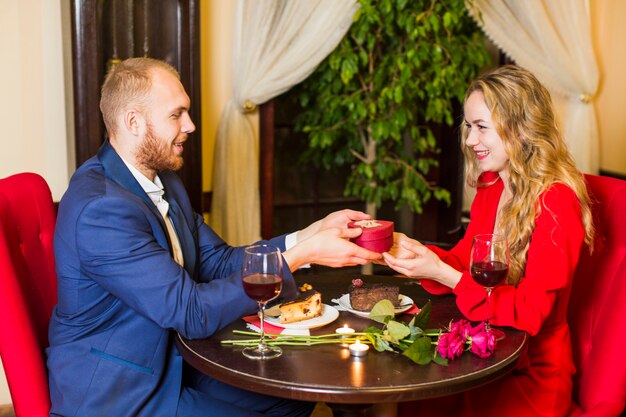 Man die geschenkdoos in hartvorm geeft aan vrouw aan tafel