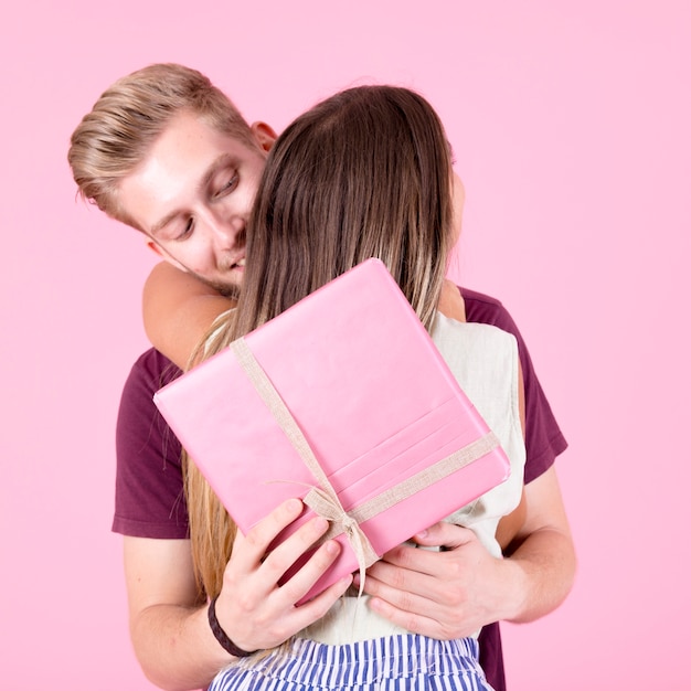 Man die haar giftdoos van de vriendinholding koesteren tegen roze achtergrond