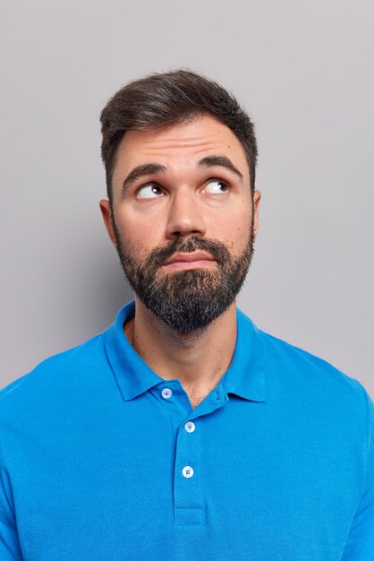 man die hierboven gefocust is, denkt dat iets donker haar heeft en draagt een casual blauw t-shirt geïsoleerd op grijs