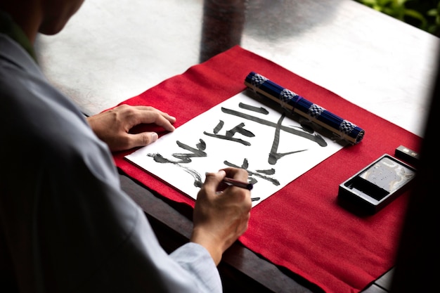 Man die Japans handschrift beoefent met een assortiment aan hulpmiddelen