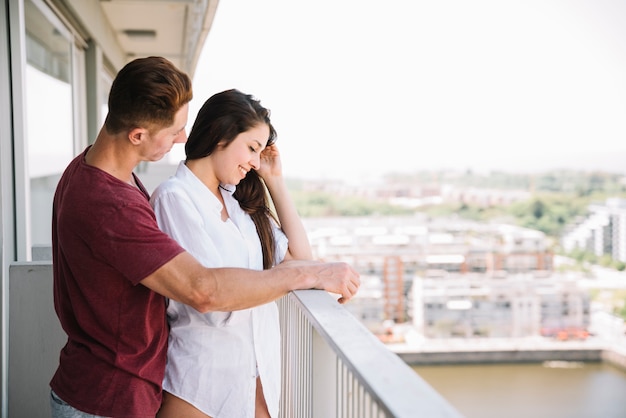 Man die jonge vrouw van erachter op balkon koestert