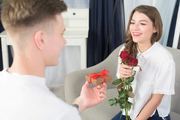 Man die kleine geschenkverpakking geeft aan gelukkige vrouw