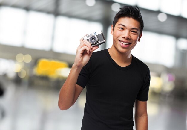 Man die lacht met een camera naast zijn hoofd