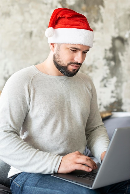 Man die met de hoed van santa zijn laptop op eerste kerstdag bekijkt