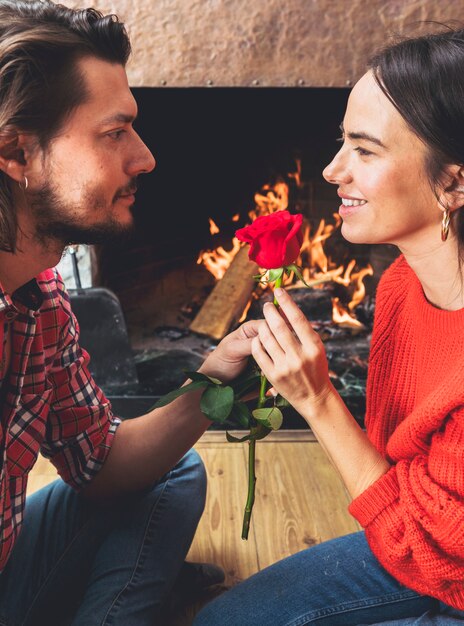 Man die rode roze bloem geeft aan vrouw op vloer