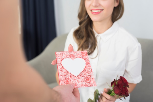 Gratis foto man die roze groetkaart geeft aan vrouw