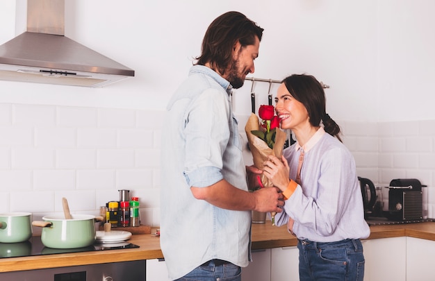 Man die rozenboeket geeft aan vrouw in keuken