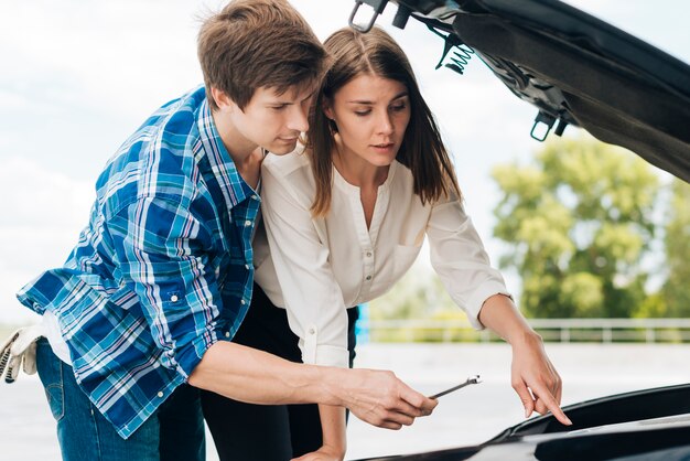 Man die vrouw helpt haar auto bevestigen