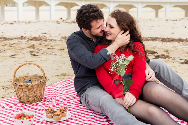 Man die vrouw met bloemen op sprei koestert