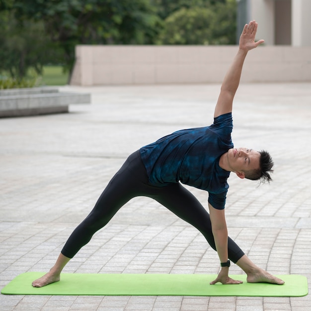 Man die zich uitstrekt tijdens het doen van yoga buitenshuis