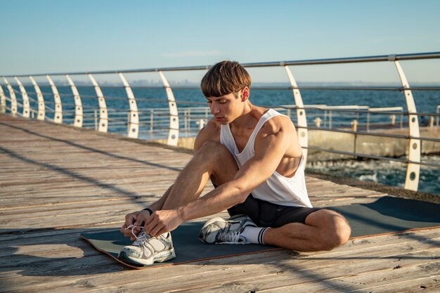 Man die zijn veters op het strand knoopt voordat hij gaat trainen