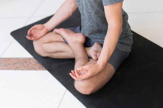 Man doet sukhasana pose op mat binnen