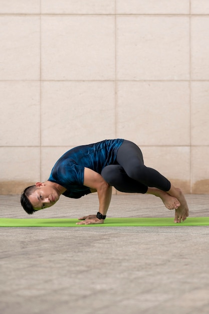 Man doet yoga buiten op de mat