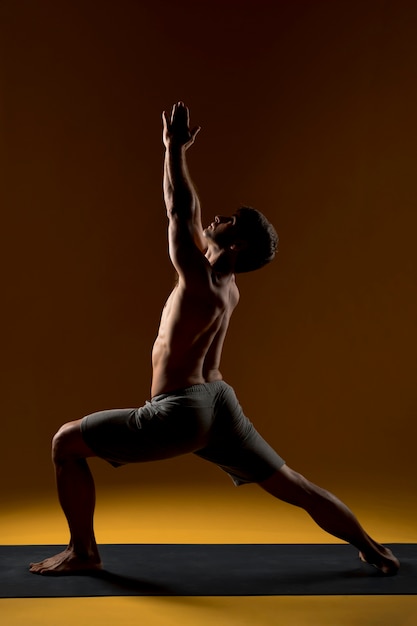 Gratis foto man doet yoga in hoge lounge pose