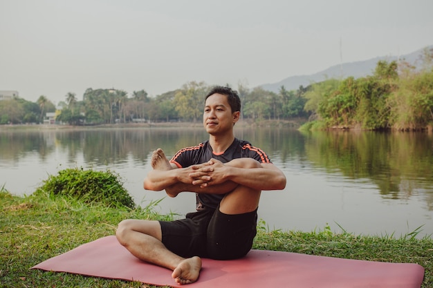 Man doet yoga naast het meer