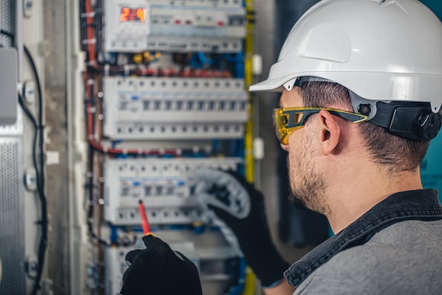 Man een elektrische technicus die werkt in een schakelbord met zekeringen