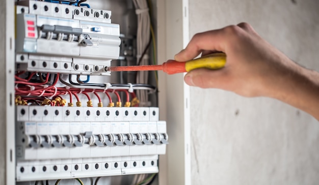 Man, een elektrotechnicus die werkt in een schakelbord met zekeringen. Installatie en aansluiting van elektrische apparatuur.