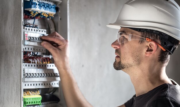 Man, een elektrotechnicus die werkt in een schakelbord met zekeringen. Installatie en aansluiting van elektrische apparatuur.