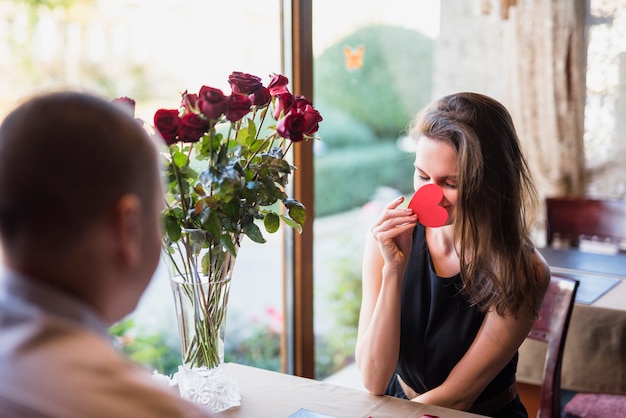 Man en jonge vrouw gezicht sluiten door ornament hart aan tafel