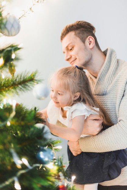 Gratis foto man en meisje die verlichte kerstboom decoreren