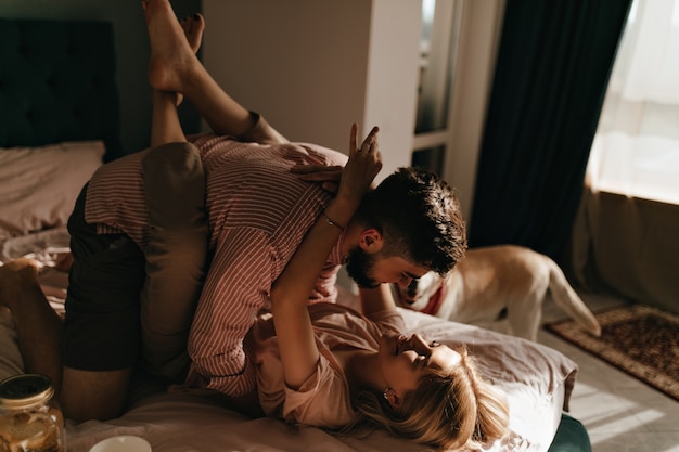 Man en vriendin omhelzen liggend in bed in een romantische sfeer. Vrouw hing als aap aan haar man.
