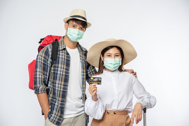 Man en vrouw gekleed om te reizen, met maskers en bagage