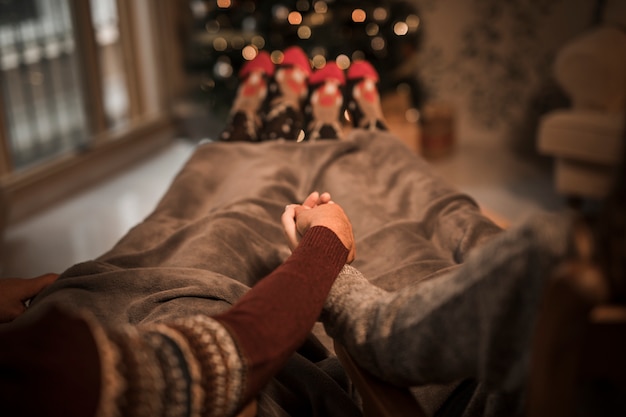 Man en vrouw hand in hand en liggend in de buurt van de kerstboom