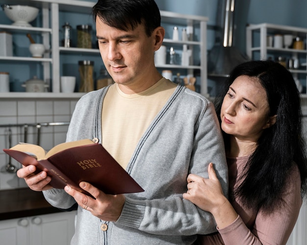 Man en vrouw in de keuken die uit de bijbel lezen