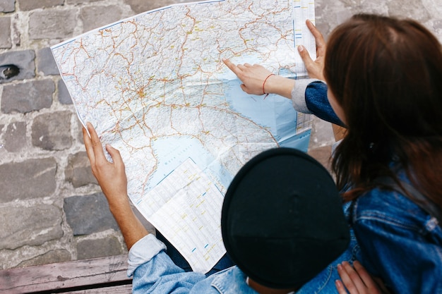 Gratis foto man en vrouw kijken naar de kaart zittend op de bank ergens in een oude stad