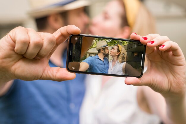 Man en vrouw nemen een selfie tijdens het kussen