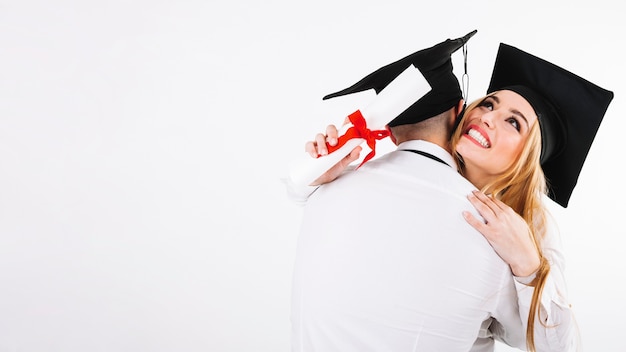 Man en vrouw omarmen met diploma's