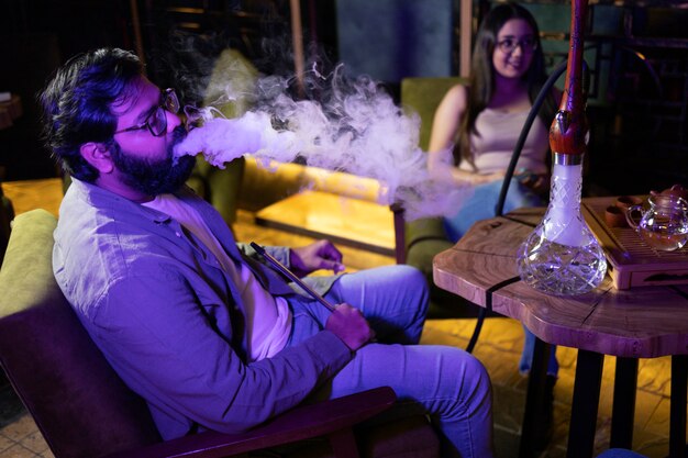 Man en vrouw ontspannen door te vapen vanaf een waterpijp in een bar