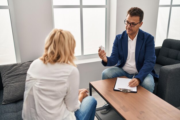 Man en vrouw van middelbare leeftijd, psycholoog en patiënt die een psychologiesessie hebben die pillen voorschrijft in het psychologiecentrum