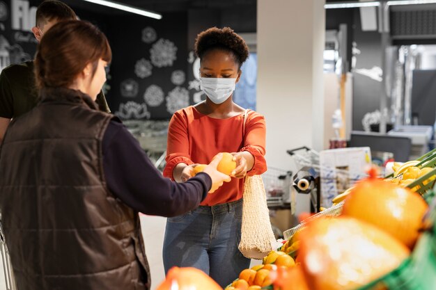 Man en vrouw winkelen in de supermarkt terwijl ze medische maskers dragen