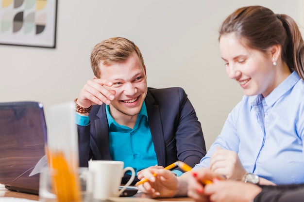 Man en vrouw zitten aan bureau glimlachen