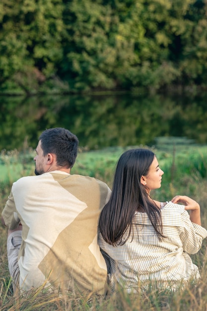 Gratis foto man en vrouw zitten bij de rivier op een zomeravond uitzicht vanaf de achterkant