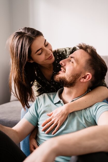 Man en vrouwenportret die aan elkaar op de bank glimlachen