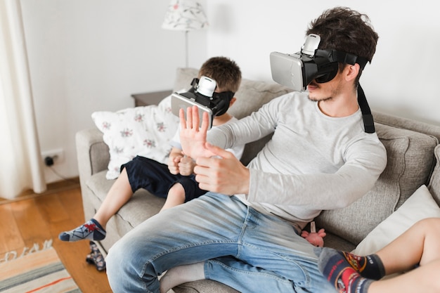 Gratis foto man en zijn kind zittend op de bank dragen van virtual reality-bril