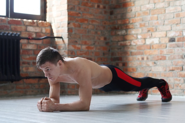 Man fitnesstraining. Shirtless mens die thuis het uitrekken doen zich