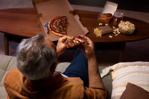 Man geniet van een pizza terwijl hij alleen thuis is