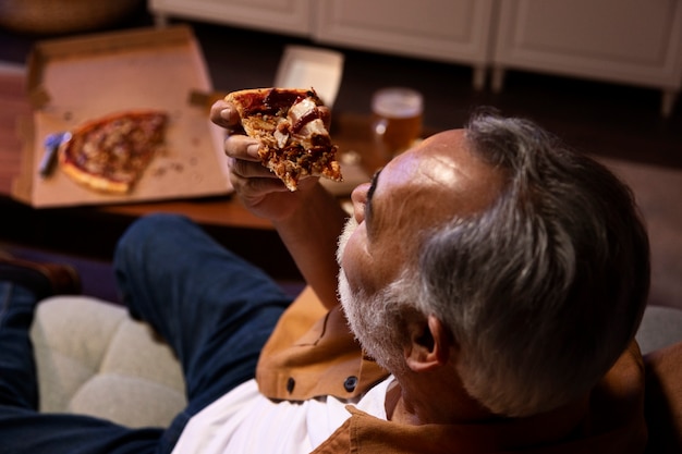 Man geniet van een pizza terwijl hij alleen thuis is