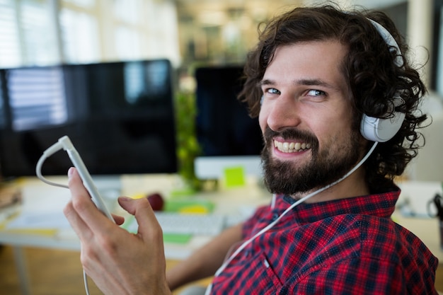 Man grafisch ontwerper luisteren muziek van mobiele telefoon