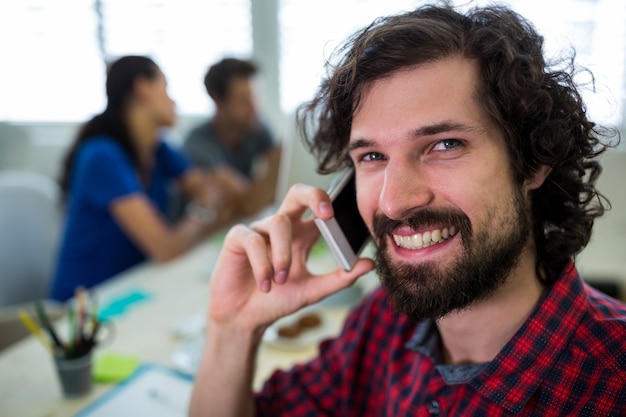 Man grafisch ontwerper praten op mobiele telefoon