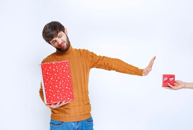 Man heeft een rode geschenkdoos en weigert een andere te nemen.