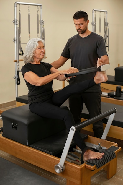 Man helpt vrouw in pilatesles.